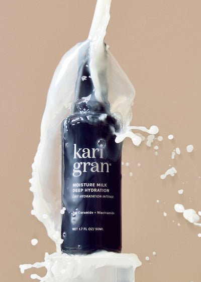 Kari Gran Moisture Milk bottle with white cream being poured over it on a beige background