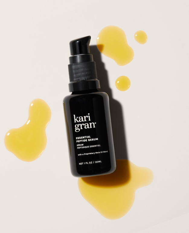 Black serum bottle with 'kari gran' branding on a beige background with yellow droplets.